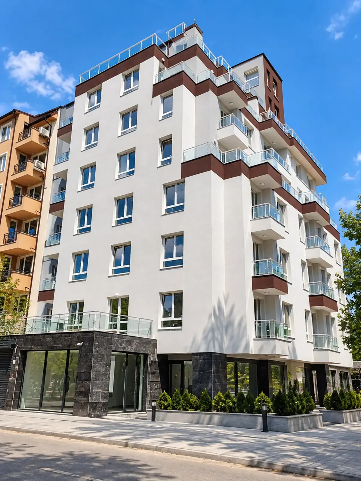 Стъклени парапети по фасадата на бяла жилищна сграда